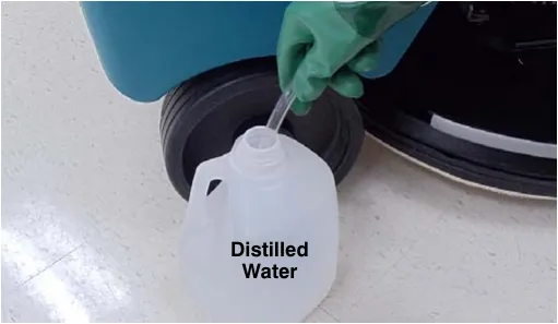 Photo of the hand pump hose end submerged in a bottle of distilled water