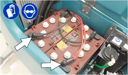 Photo of the battery cables with arrows pointing to the connections to disconnect