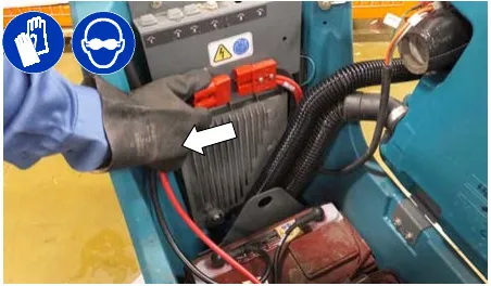 Photo of a gloved hand disconnecting the battery cable connection at the machine