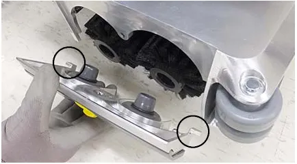 Photo of the idler plate being connected to the brush ends with the idler plate hooks circled