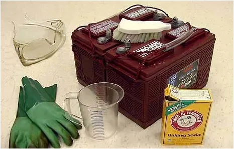 Photo of battery cleaning supplies: safety glasses, gloves, scrub brush, measuring cup and baking soda
