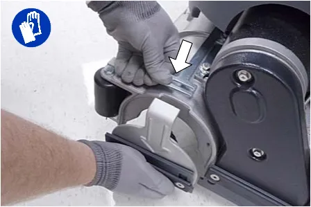 Pressing the spring tab downward to remove the idler plate from the scrub head