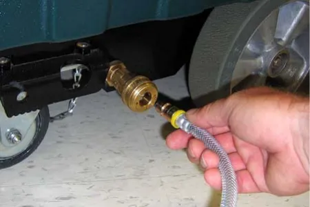 Connecting the solution hose to the coupler at the lower right side of the machine