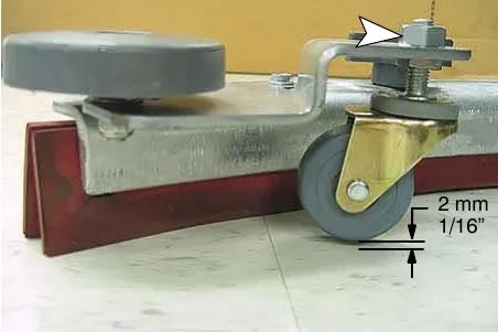 Adjusting the squeegee caster (arrow) with the assembly on a level surface; blade clearance of 1/16 in (2 mm)