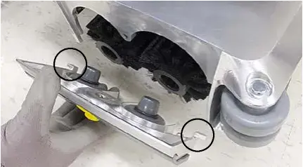 Idler plate being reattached to the brush ends, circles marking the idler plate hooks