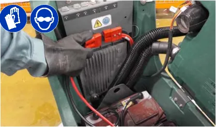 Hand disconnecting the battery cable connection at the machine