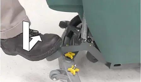 Foot stepping down on the scrub head lift pedal, arrows showing the motion