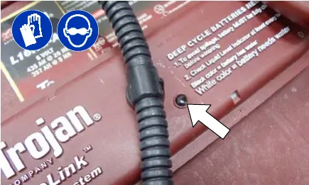Electrolyte level indicator on a battery cover, arrow pointing at it