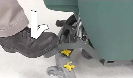 Foot stepping down on the scrub head lift pedal, arrows showing the motion