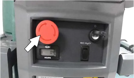 Red emergency shut-off button on the control console, arrow pointing at it