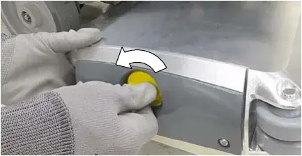 Yellow knob being unscrewed to remove the idler plate from the scrub head
