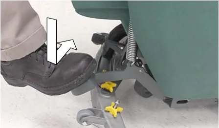 Foot stepping down on the scrub head lift pedal, arrows showing the motion