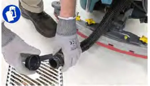 Gloved hands removing the drain hose cap over a floor drain to drain the recovery tank