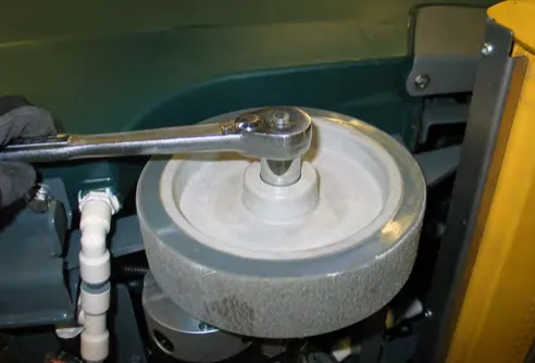 Removing the wheel nut from the left drive wheel with a wrench