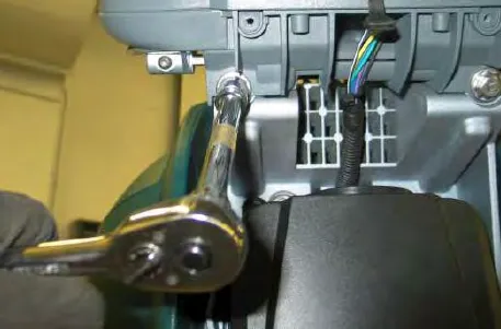 Removing an operator console mounting bolt with a ratchet wrench