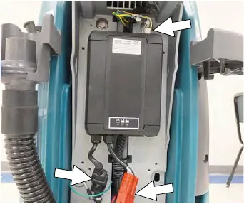 The battery charger in the machine with arrows at the cable and harness connections and the mounting screws