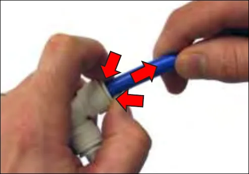 Pushing the collet in against the fitting while pulling the blue tube out, with red arrows