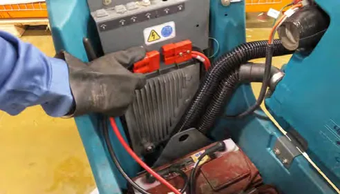 Gloved hand disconnecting the red battery connectors