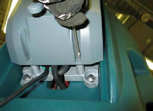 Removing a rear access cover mounting screw with a screwdriver
