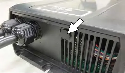 Underside of the charger with an arrow pointing at the black cap over the profile dial
