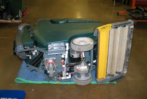 Machine lowered onto its left side on a blanket, showing the transaxle and wheel