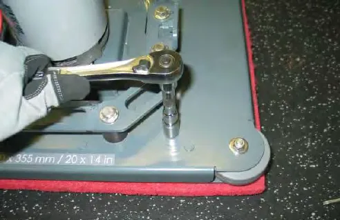 Loosening a nyloc nut on a lower isolator with a ratchet wrench, scrub head on a work bench