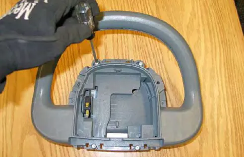 Removing a screw from the front of the operator’s console