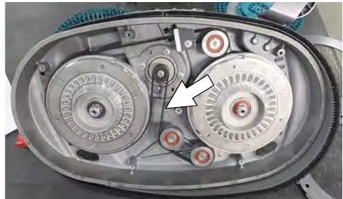 Underside of the disk scrub head with the cover off and an arrow pointing to the drive belt