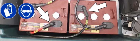 Battery cable connections being disconnected; protective gloves and eye protection symbols