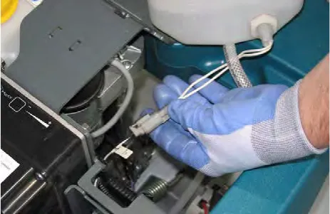 Gloved hand disconnecting the wire harness from the liquid level sensor