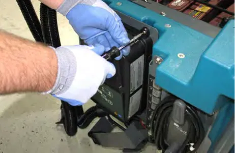 Gloved hands lifting the on-board battery charger out of the machine