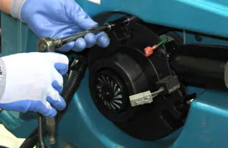 Gloved hands removing the vacuum fan mounting hardware