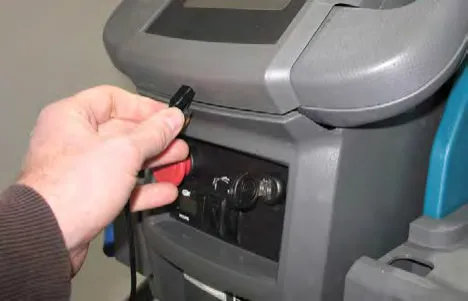 Hand plugging a USB cable into the port on the control console