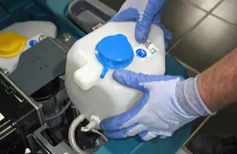 Gloved hands lifting the ABW tank from the machine