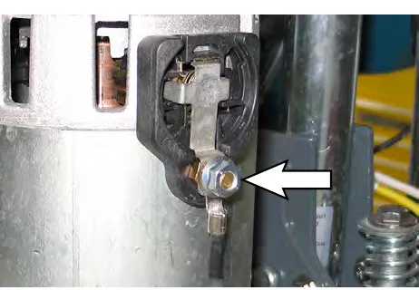 Arrow pointing to the hex nut securing the cable to the brush motor
