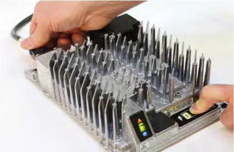 Hand reconnecting the AC cable while a finger presses the Select Charge Profile button on the charger