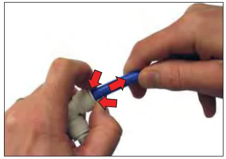 Fingers pushing the collet of a push-to-connect fitting while the hose is pulled out, with red arrows