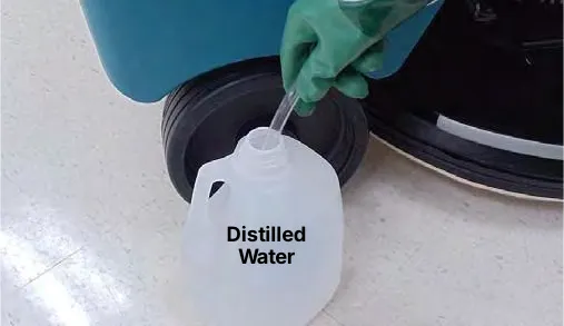 Hand pump hose placed in a jug labeled Distilled Water