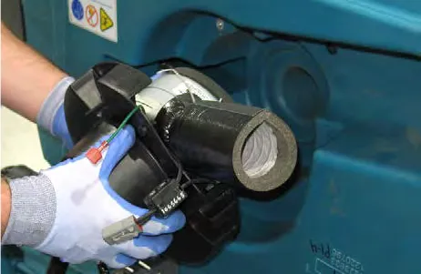 Gloved hands lifting the vacuum fan assembly from the machine