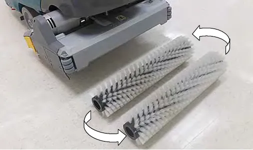 Two cylindrical brushes removed from the scrub head with arrows showing them swapped front to rear