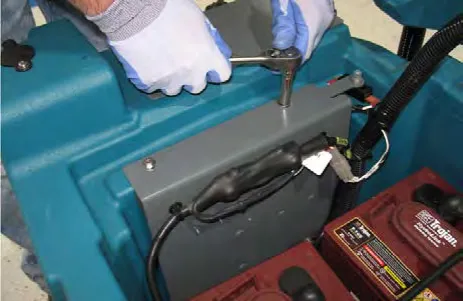 Hand reaching in to remove the hardware that holds the electrical mounting bracket