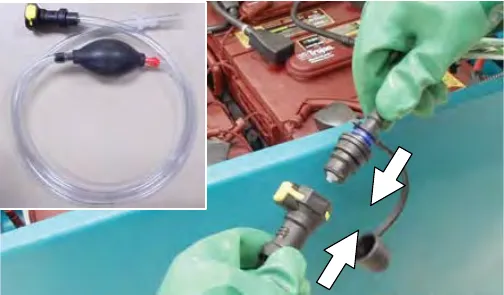 The hand pump hose and a gloved hand connecting it to the battery fill hose coupler after removing the dust cap