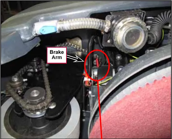Photo looking at the front drive wheel area with a red circle around the red brake arm on the drive wheel motor, labeled Brake Arm