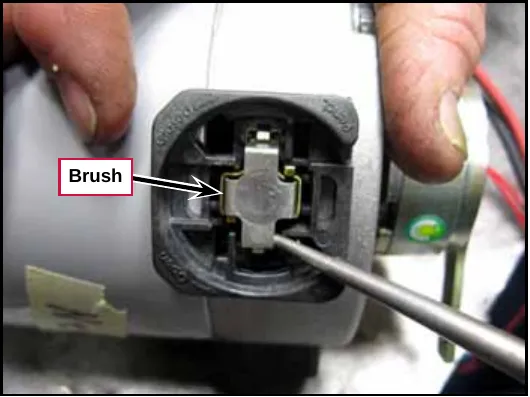 Photo of the open brush holder with the brush being pried out with a screwdriver