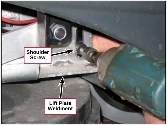 Impact driver removing the shoulder screw that joins the scrub deck actuator to the lift plate weldment. Labels: Shoulder Screw, Lift Plate Weldment.