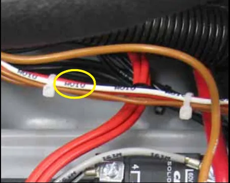 Close-up of the machine wiring harness with a white wire marked W010 circled in yellow