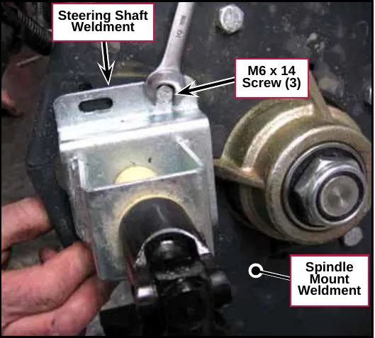 Photo of the steering shaft weldment with a wrench on one of its three M6 x 14 screws, next to the spindle on the spindle mount weldment