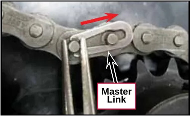 Close-up photo of pliers on the master link of the chain, with a red arrow showing the direction to slide it