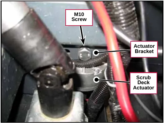The M10 screw holding the scrub deck actuator to its bracket on the machine frame. Labels: M10 Screw, Actuator Bracket, Scrub Deck Actuator.