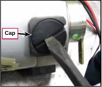 Photo of a flat screwdriver removing the black cap from the motor brush holder